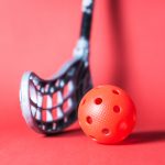 Floorball,Stick,And,Ball,Against,Red,Background.,Floor,Hockey,Concept.